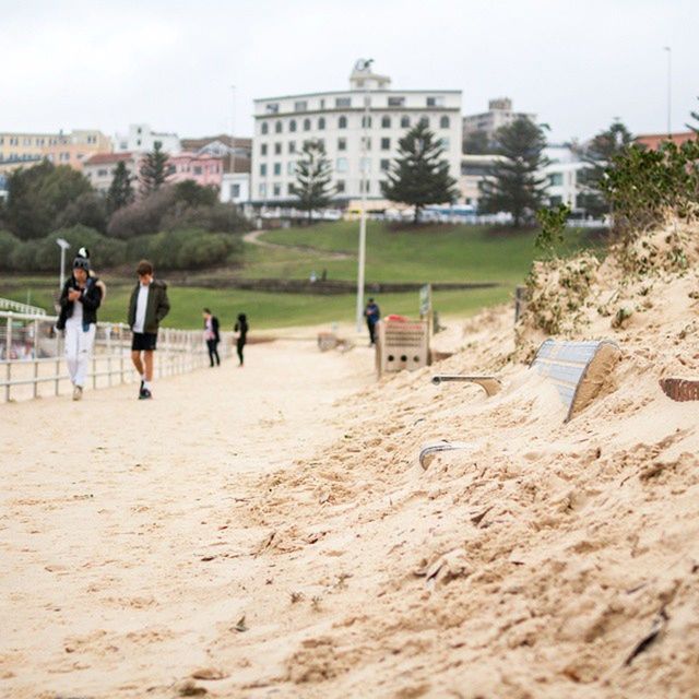 building exterior, architecture, built structure, lifestyles, leisure activity, men, walking, large group of people, person, sand, tourist, full length, city, beach, day, sky, tourism, city life, mixed age range