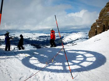 People standing on snow covered landscape against sky