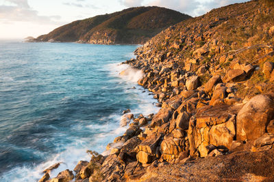 Scenic view of rocky shore and sea against sky