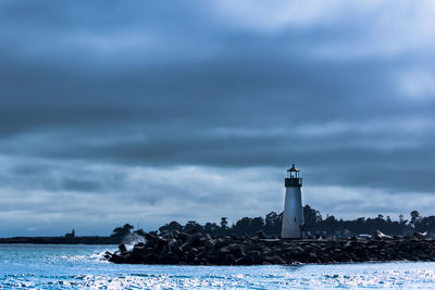 Lighthouse by sea against sky