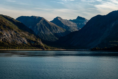 Scenic view of lake by mountains against sky