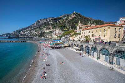 View of houses on mountain by sea against clear blue sky during sunny day