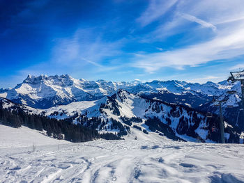 Scenic view of snowcapped mountains against blue sky