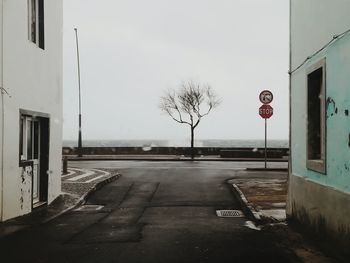 Road sign by building against sky