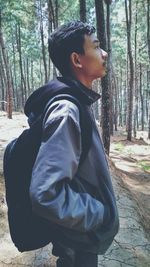 Side view of young woman standing in forest