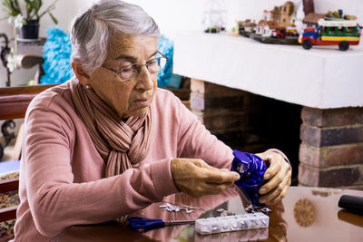 Senior woman taking medicine while sitting by table at home