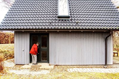 Full length of woman locking door of house