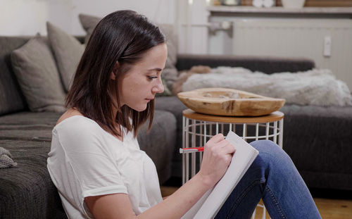 Side view of young woman sitting on sofa at home