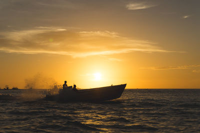 Silhouette boat in sea against sky during sunset