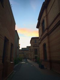Road leading towards buildings at sunset