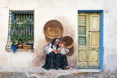 Woman standing by window of building