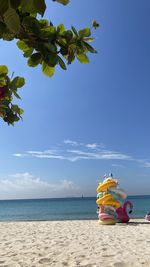 Rear view of woman sitting on beach against clear blue sky