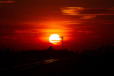 Scenic view of silhouette road against orange sky