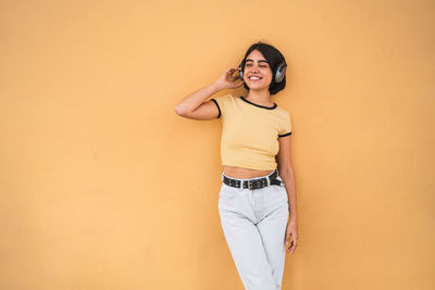 Portrait of smiling young woman standing against wall