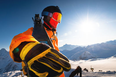 Close-up portrait of a guy holding skis in winter, he is wearing sportswear such as a helmet and