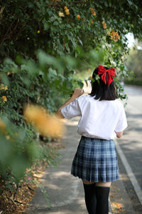 Rear view of woman standing by plants outdoors