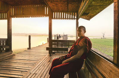 Monk sitting on bench at lake