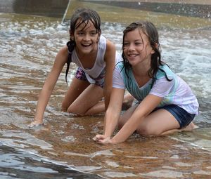 Portrait of happy girl sitting in water