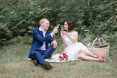 Full length of bride and bridegroom toasting champagne flutes on field