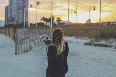 Young woman standing at beach during sunset