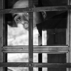 Portrait of woman looking through window in building