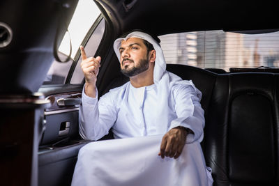 Man pointing away while sitting in car