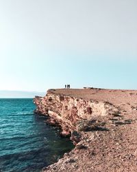 Distant view of people standing at beach against sky