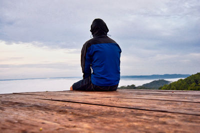 Rear view of man looking at sea against sky