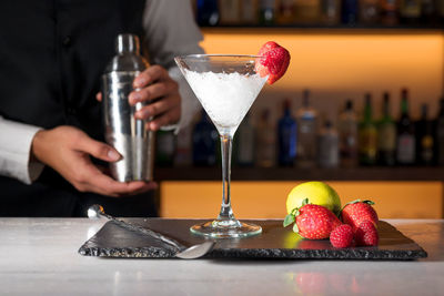 Midsection of woman holding drink on table