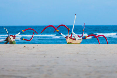 Outriggers at beach against sky