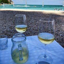 Close-up of drink on table at beach against sky