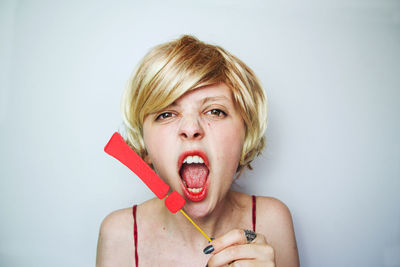 Portrait of young woman holding exclamation point against white background