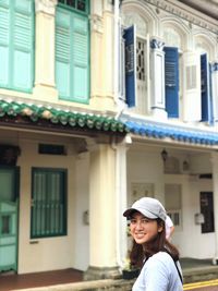 Portrait of woman standing against building in city