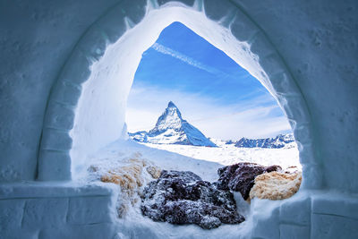 View of matterhorn peak seen through ice igloo on snowy landscape