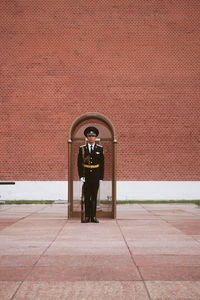 Portrait of man standing against brick wall