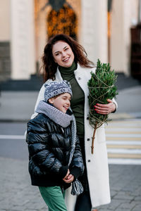 Portrait of a charming mother and son with a small christmas tree in their hands. 