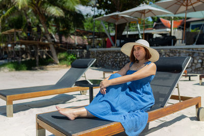 Asian woman in blue dress in summer on the sand on the beach of tropical island.