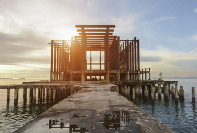 Pier on sea against sky during sunset