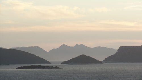 Scenic view of sea and mountains against sky