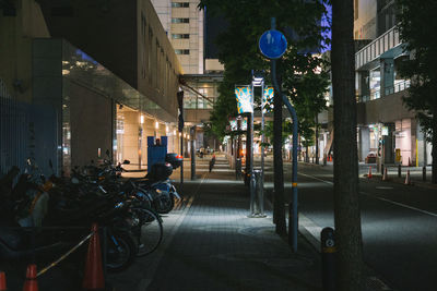 Illuminated street amidst buildings in city at night