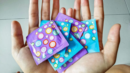 Cropped hands holding condoms indoors
