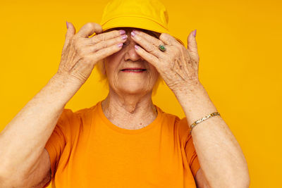 Midsection of woman with face against yellow background