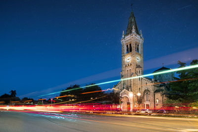 Light trails on road against buildings at night