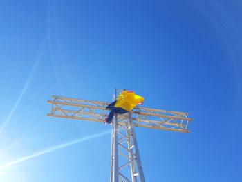 Low angle view of crane against clear blue sky