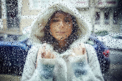 Portrait of woman seen through wet window in rainy season