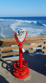 Close-up of coin-operated binoculars by sea against sky