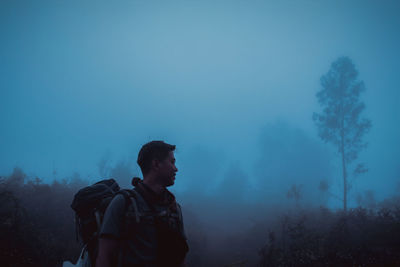 Rear view of man standing against foggy sky