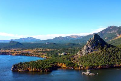 Scenic view of lake and mountains against clear blue sky