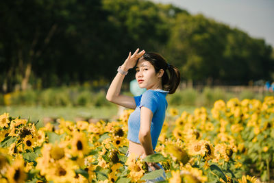 Young woman standing amidst flowering plants on field