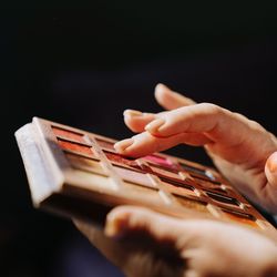 Close-up of hand holding smart phone against black background